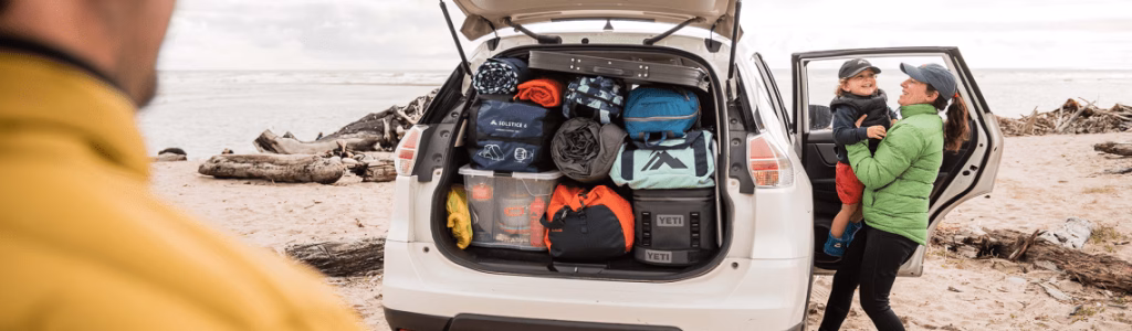 Your Camping Checklist for First Timers: Embrace the Great Outdoors Family preparing for a beach camping trip with a fully packed SUV trunk including coolers, sleeping bags, and storage containers, with ocean view in the background