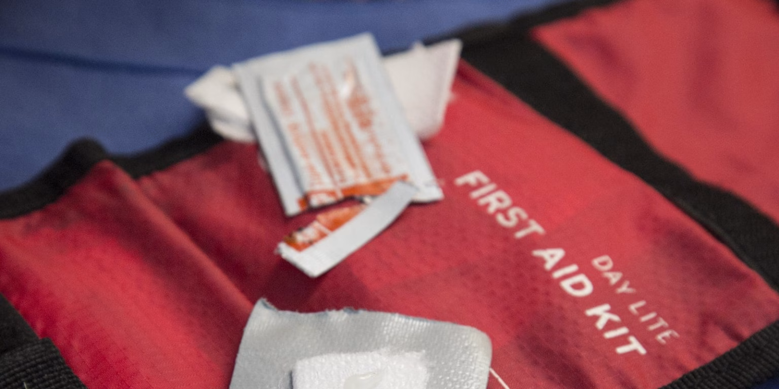 The First Aid Kit for Camping Adventures: Your Essential Companion Close-up of a red first aid kit labeled "DAY LITE FIRST AID KIT" with opened antiseptic wipes and bandages on top.